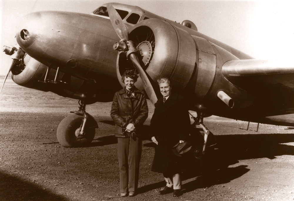 Amelia Earheart standing with Lockheed Electra plane at Bendix Field