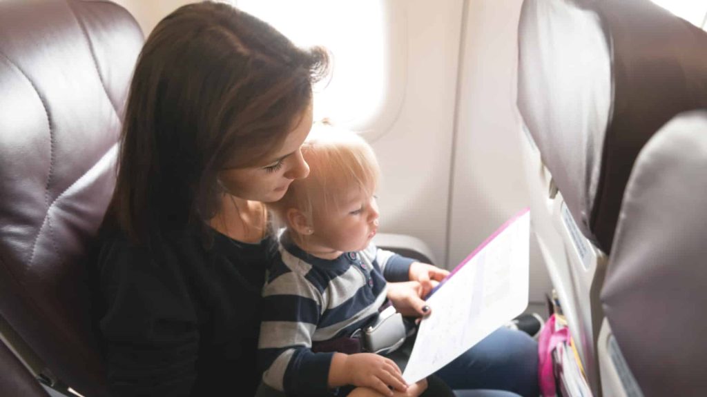 Mother and her daughter checking safety in economy class airliner